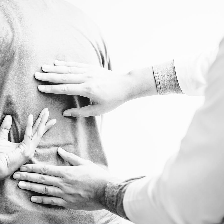 black and white image of three hands touching a back