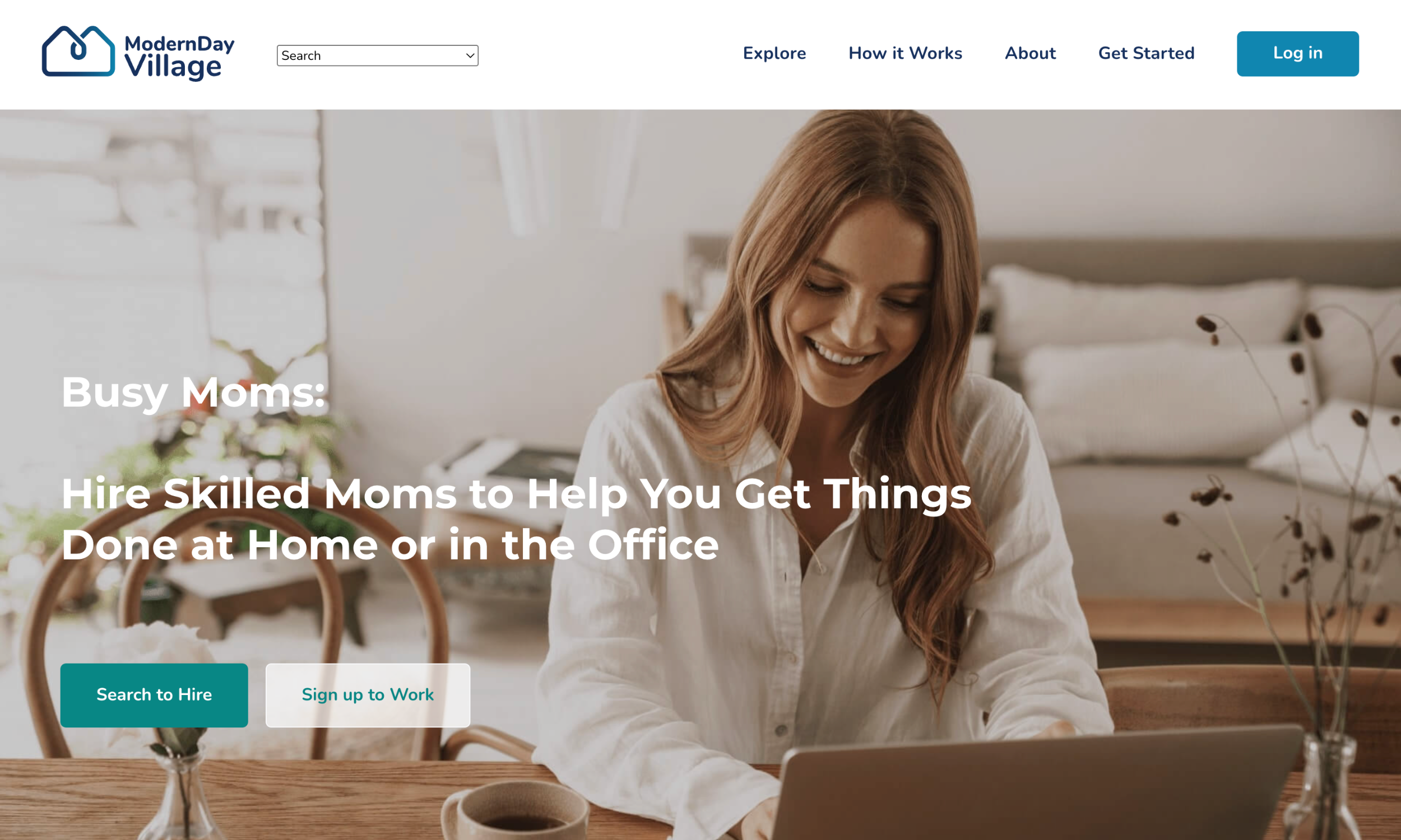 A woman sits at a desk, smiling and using a laptop. The website header reads "ModernDay Village" with options to search, explore, and log in. Text promotes hiring skilled moms and networking for moms seeking new opportunities.