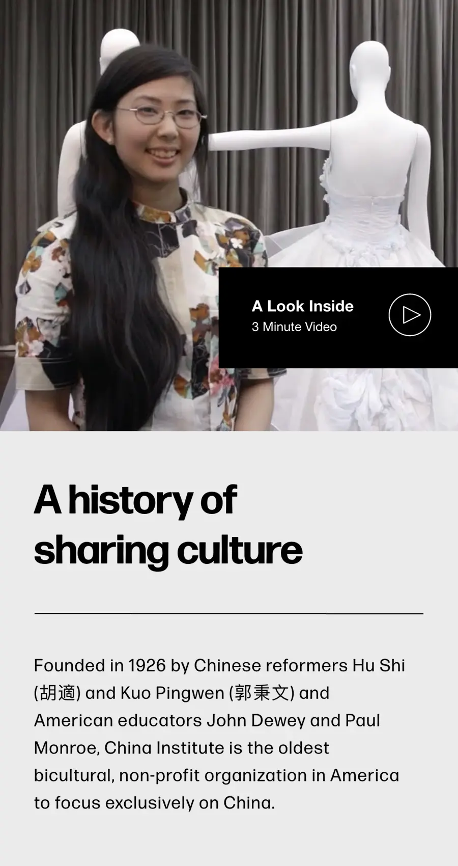 A woman stands smiling in front of two white dress forms wearing sculptural gowns, beside a display exploring the rich history of the China Institute.