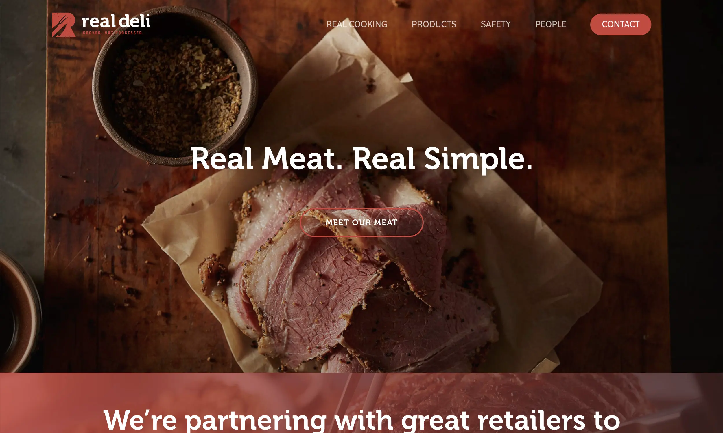 Slices of deli meat on parchment paper with a bowl of spices on a wooden surface; "Real Meat. Real Simple." text overlay.