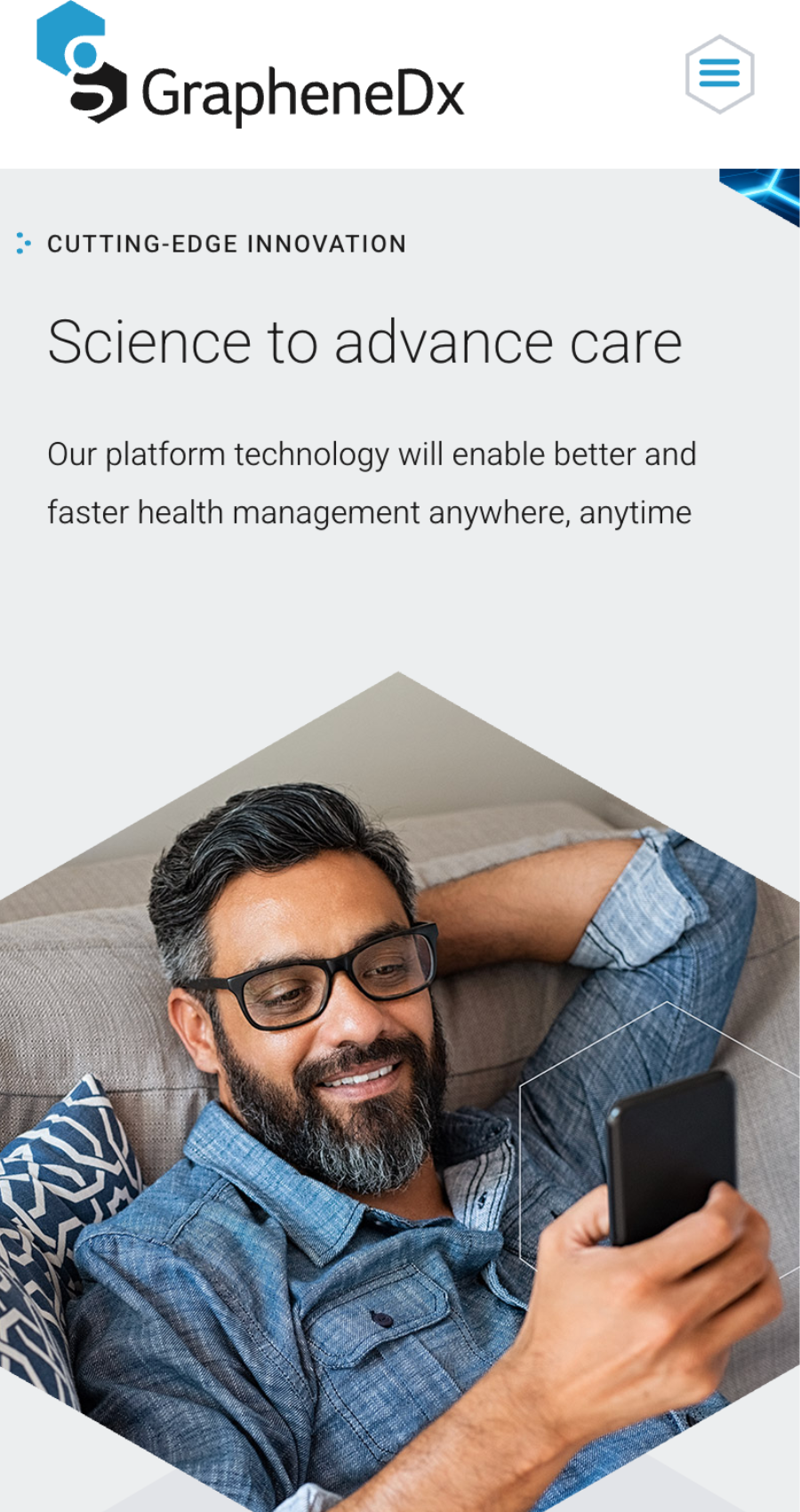 A man with glasses and a beard sits on a sofa, smiling while looking at his smartphone; the text showcases GrapheneDx’s telehealth website design for advanced health management technology.