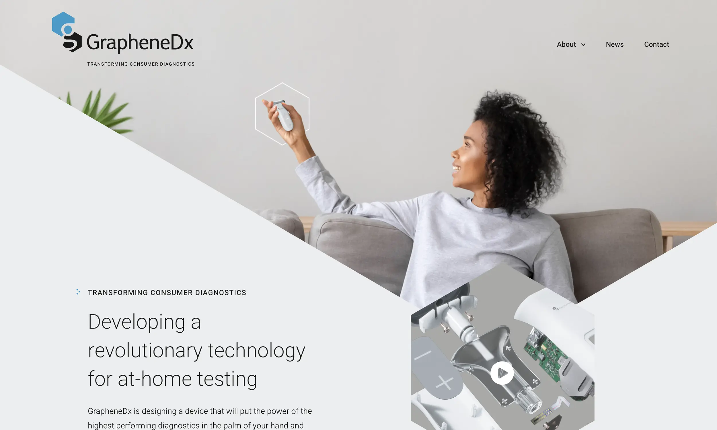 A woman sits on a gray sofa, smiling and holding up a small white device. The website header reads "GrapheneDx: Transforming Consumer Diagnostics.