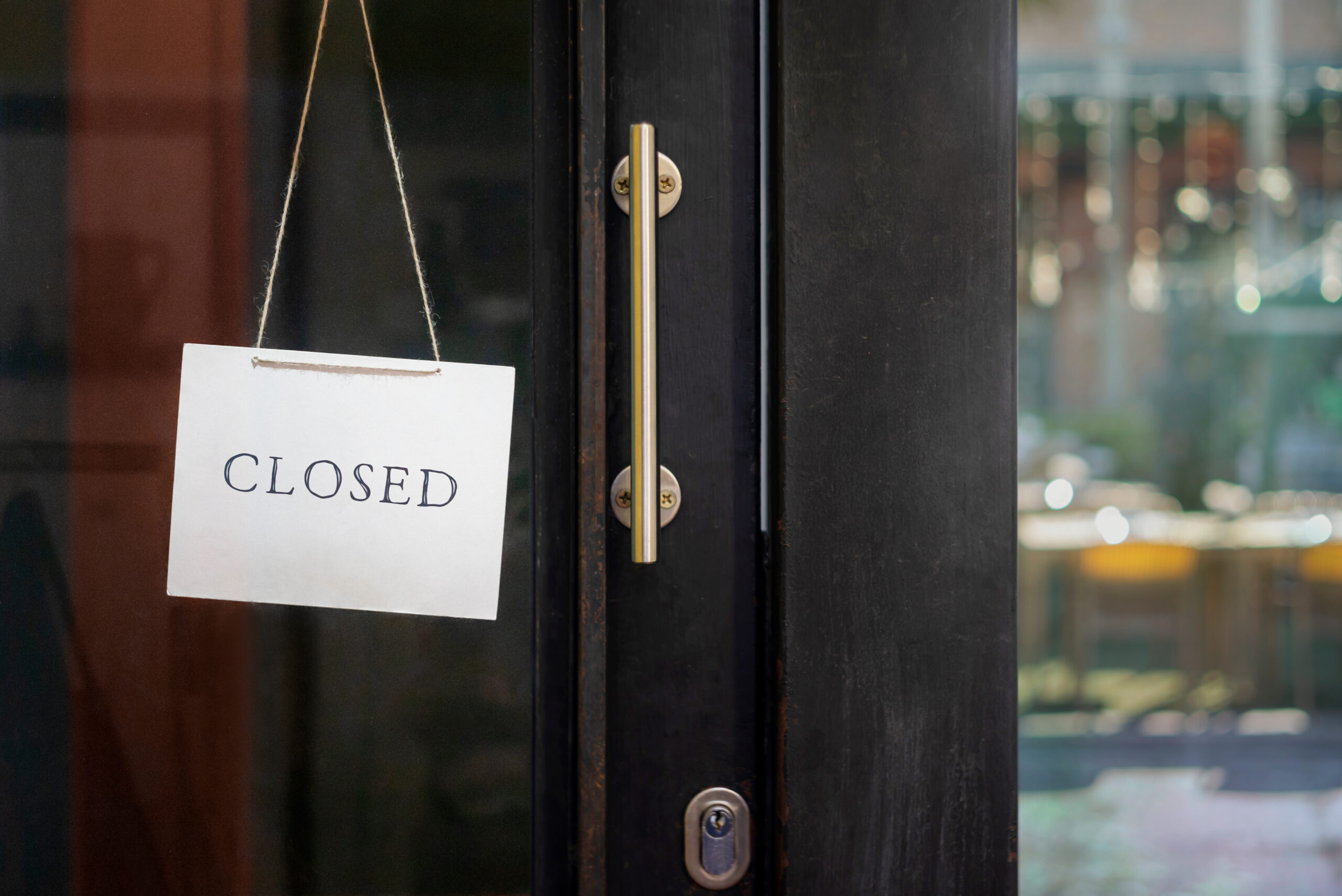 A white sign with the word "CLOSED" hangs on a glass door next to a vertical metal handle, visually echoing the frustration of encountering a website outage.
