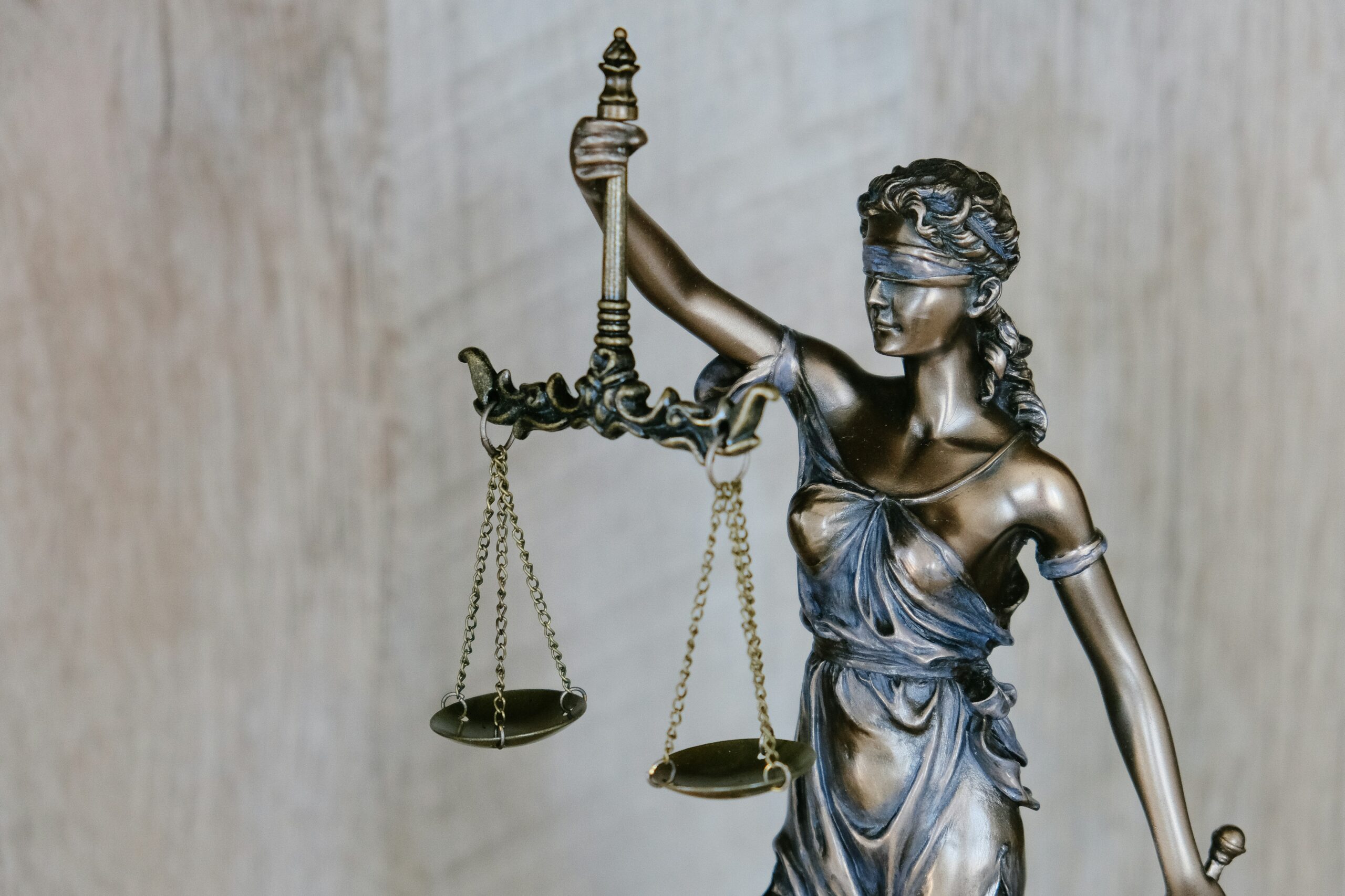 A bronze statue of Lady Justice, symbolizing fairness, stands blindfolded and holding balanced scales and a sword—an iconic image often found in the office of an NYC Attorney.
