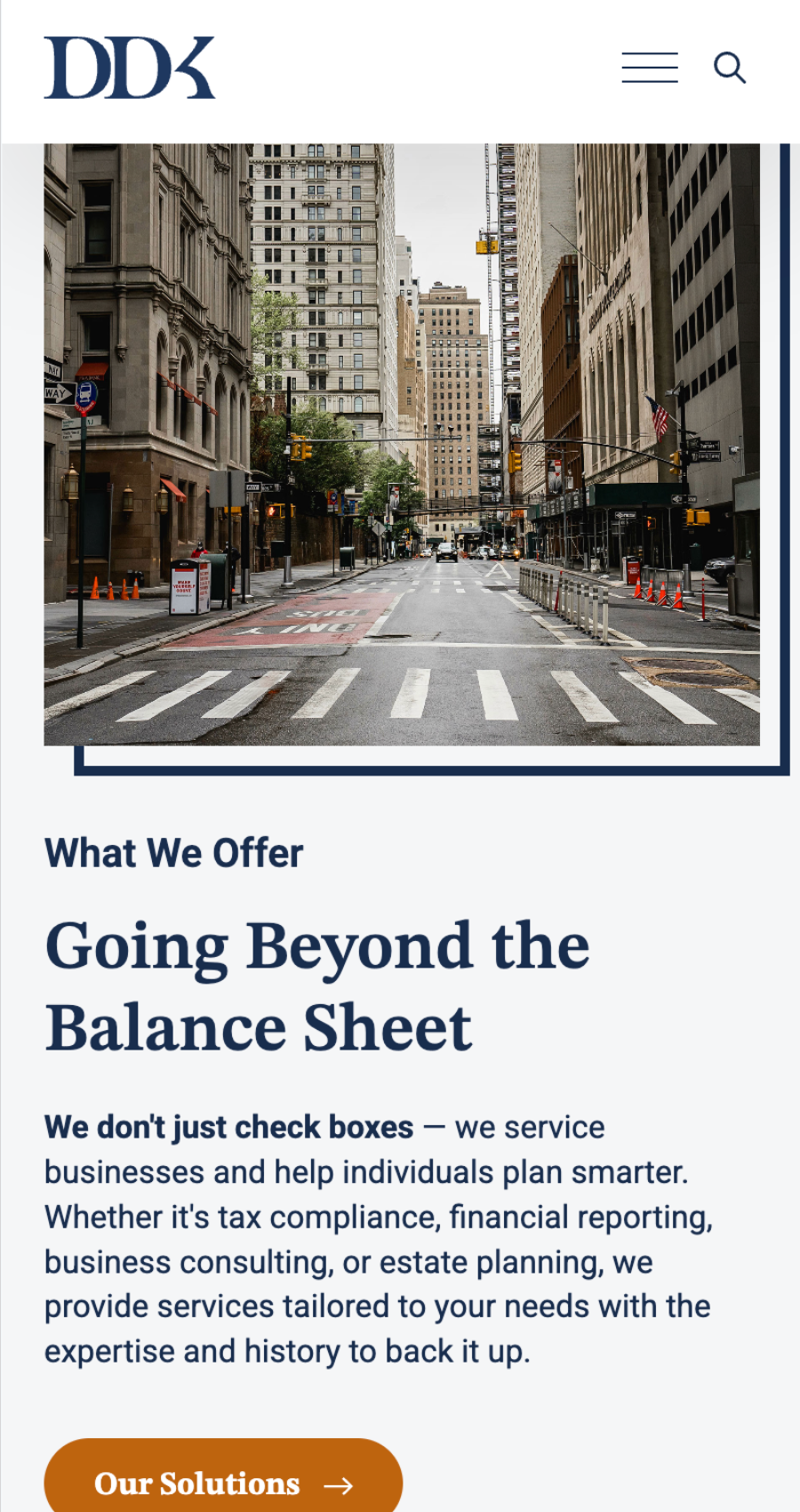 A city street with tall office buildings and an empty crosswalk, featured on a business service website offering financial and consulting solutions.
