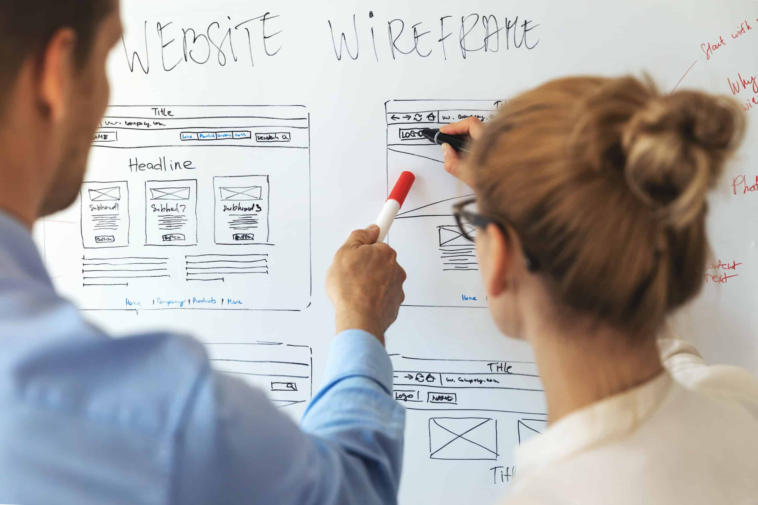 Two UI UX designers following an issue on a whiteboard