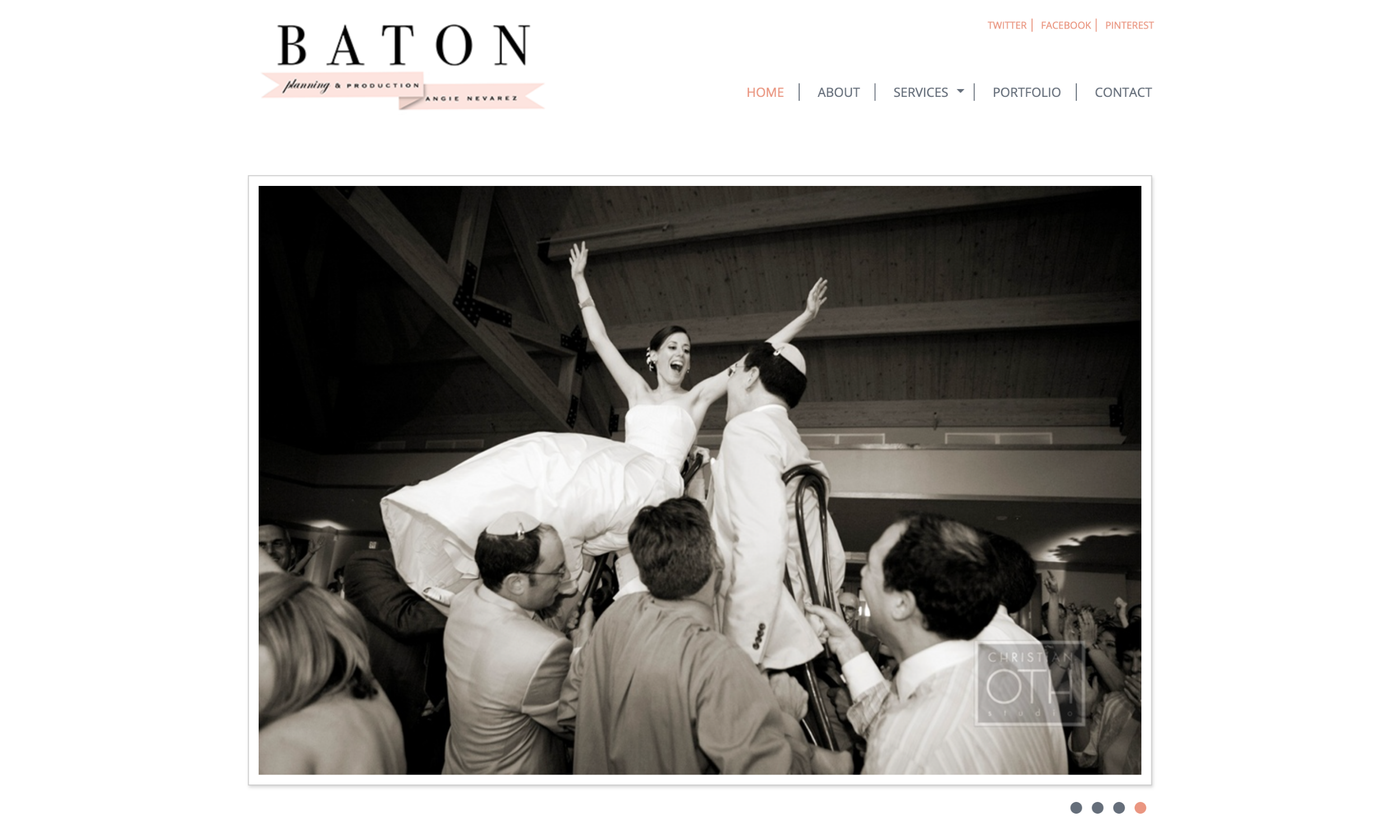 A bride and groom are lifted on chairs by guests during a wedding celebration in a large reception hall.
